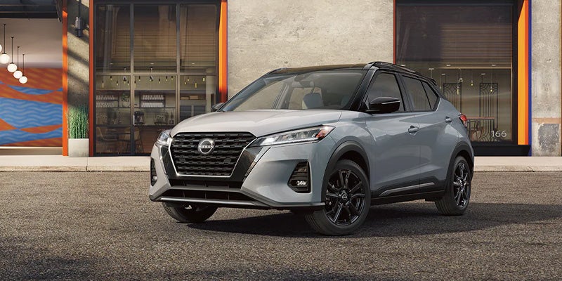 A silver Nissan Kicks sitting in front of a dealership.