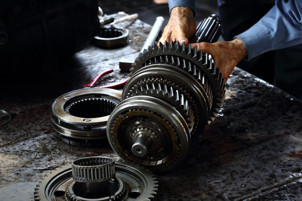 A picture of an automotive transmission, partially disassembled, held by a service technician's hands.